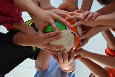 ball-952311_1920-1.jpg Bild aus der Froschperspektive. Viele Hände halten zusammen einen Fußball.