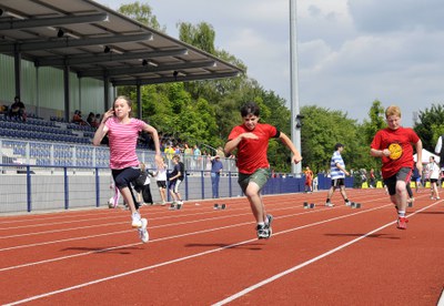 Abschlussarbeiten Kinder laufen ein Rennen, draußen in einem Leichtathletikstadion